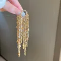 Nahaufnahme der goldenen Metallblatt-Quastenohrringe mit schimmerndem Lagen-Design - Goldblatt-Quasten-Ohrclip