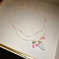 Close-up of a double-layer crystal beaded necklace with cute strawberry and cherry pendants. - Gold-Pink-White