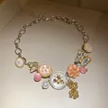 Macro view of crystal rhinestone enamel bee and flower pendants on a statement necklace - Gold-Silver-Pink