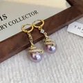 Close-up of elegant snake-shaped earrings with purple pearls and pavé stones. - Snake with Purple Pearl / Purple Pearl Gold Style