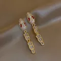 Elegant gold-plated snake drop earrings featuring clear zircons and striking red crystal eyes - Snake Dangle Style / Gold