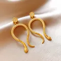 Elegant gold snake earrings encrusted with sparkling crystals placed on silk background - Arc Snake Drop Style / Gold