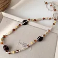 Detailopname van een Boheemse tailleketting met kralen van hout en amberkleurige hars. - Vintage Gevlochten Kralenstijl (11#)
