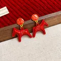 Detailed close-up view of red oil-drop horse earrings with festive gold Fu character - Blessing Horse Style / Red