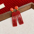 Detailed close-up of festive red New Chinese style earrings with lucky characters - Immediate Wealth Style / Red