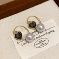 Macro detail of French vintage gold heart earrings with grey crystal and white pearl - Ear Hook Style / Gold Black
