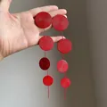 Close-up of red textured circular disks on long drop tassel earrings for women. - Round Tassel Style / Red