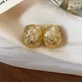 Vista macro dettagliata della trama intrecciata degli orecchini a clip placcati oro 18k - Oro
