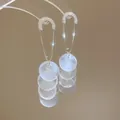 Dettaglio di eleganti orecchini a spilla dorati con pendenti in conchiglia bianca. - Stile 49