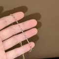 Gros plan d'un délicat bracelet doré orné de zircons carrés multicolores étincelants - Or-Multicolore
