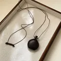 Dettaglio di una collana vintage in legno scuro su un vassoio da esposizione strutturato - Stile 58 (58#)