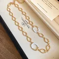 Detaillierte Nahaufnahme einer vergoldeten ovalen Gliederkette mit weißer Emaille - Halskette / Gold/Weiß
