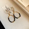 Detailansicht eleganter gold-schwarzer emaillierter ovaler Ohrhänger auf einem Tablett - Ohrringe / Gold/Schwarz