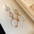 Nahaufnahme von eleganten Vintage-Ohrhängern mit Gold- und weißem Emaille-Finish. - Ohrringe / Gold/Weiß