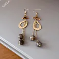 Close-up of ethnic retro earrings with irregular gold hoops and wooden beads - Hook Style / Gold Brown