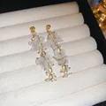 Detailed close-up of retro floral earrings with frosted white petals and gold chains. - Korean Gentle Floral Style