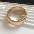 Close-up of a polished gold-finished chunky acrylic bangle with geometric curves - Round / Medium / Gold