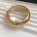 Close-up of a chunky gold-toned acrylic geometric bangle with a polished finish. - Round / Small / Gold