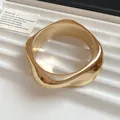 Close-up view of gold geometric acrylic bangle featuring a wavy irregular faceted design - Spiral Type / Gold