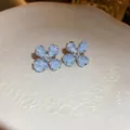 Close-up of light blue flower stud earrings with crushed stone petals and center gem. - Clover Crushed Stone Texture Studs (3#)