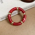 Detailed view of red marbled acrylic tube bracelet with gold spacers on vintage book - Red Marble Pattern Acrylic Bracelet / Red