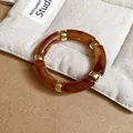 Detailed view of an acrylic amber marble bracelet featuring gold-tone square spacers - Amber Pattern Arc Segment Bracelet / Dark Coffee