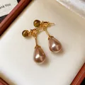 Close-up view of vintage Maillard style drop earrings with tiger eye stone and teardrop pearl - Gold Brown