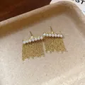 Orecchini dorati a perno con nappe e perle in un vassoio minimalista - Stile con perno dell'orecchino in argento / Oro