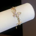 Close-up detail of a gold-tone bracelet featuring sparkling zircon-encrusted butterflies. - Gold