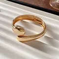 Vista detallada de un brazalete dorado pulido en un elegante expositor de joyas blanco - Estilo Pulido De Lágrima Cruzada (5#) / Grande / Dorado