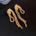 Elegant gold-colored knotted mesh chain tassel earrings on a black background - Large / Gold