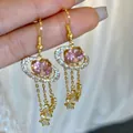 Eleganti orecchini a pianeta con zirconi rosa e nappe a stella in una finitura dorata lucida - Stile Gancio per Orecchio con Nappa e Anello di Saturno in Zirconia Rosa (76) / Rosa Oro