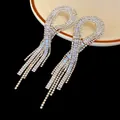 Macro view showing the sparkle of long zircon geometric tassel earrings on a plate - Geometric Tassel Style / Silver