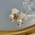 Close-up of elegant flower-shaped stud earrings with sparkling crystals and white pearls - Silver Post (HE14435) / Gold