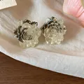 Close-up of elegant resin rose flower stud earrings with shimmering gold finish - Light Gray and Beige