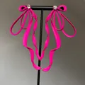 Detailed view of these oversized neon pink bow earrings with sparkling rhinestone accent - Pink