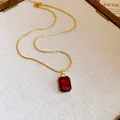 Close-up of a vintage gold necklace featuring a luxury red square gemstone pendant - Necklace / Gold/Red