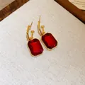 Detailed macro shot of vintage-style gold earrings with red rectangular gemstones - Earrings / Silver Needle / Gold/Red