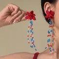 Close-up of vibrant red flower earrings with colorful blue and red beaded tassels on model - 12#