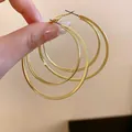 Detailed close-up of triple-layered golden hoop earrings with steel pins. - 多层圆环(HE23342) / Gold