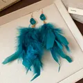Dramatic peacock blue feather tassel earrings with gold hooks on a textured cream tray. - Feather Tassel Style (HE23665) / Gold-Blue