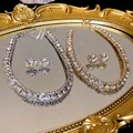 Elegant gold-tone jewelry set with square diamond studs and paved rhinestone necklace. - Gold