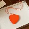 Close-up detail of orange heart-shaped leather sunglasses storage pouch necklace - Necklace / Orange