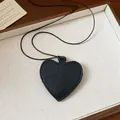 Close-up of black pebbled leather heart pendant sunglass holder on thin cord necklace - Necklace / Black
