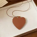 Detail view of brown heart-shaped leather pendant with textured finish on brown cord. - Necklace / Brown