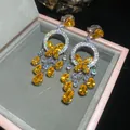 Dettaglio di orecchini di lusso con farfalla in pietre gialle e nappe a forma di pera - Stile Giallo (12#)