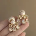 Primer plano de elegantes pendientes de perlas y diamantes de imitación bañados en oro. - Perla Gota de Agua (HE20080) / Pack de 1 par / Dorado