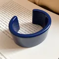 Dettaglio di un bracciale a fascia in resina blu scuro posizionato su un libro aperto. - Stile Blu Scuro(4#)