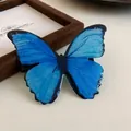 Detail view of a vibrant blue butterfly hair clip with shimmering forest style details. - Small Alligator Clip / Blue