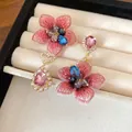 Dettaglio di orecchini asimmetrici a fiori rosa e gocce di strass su vassoio portagioielli - Stile Goccia Fiore Asimmetrico / Oro-Rosa